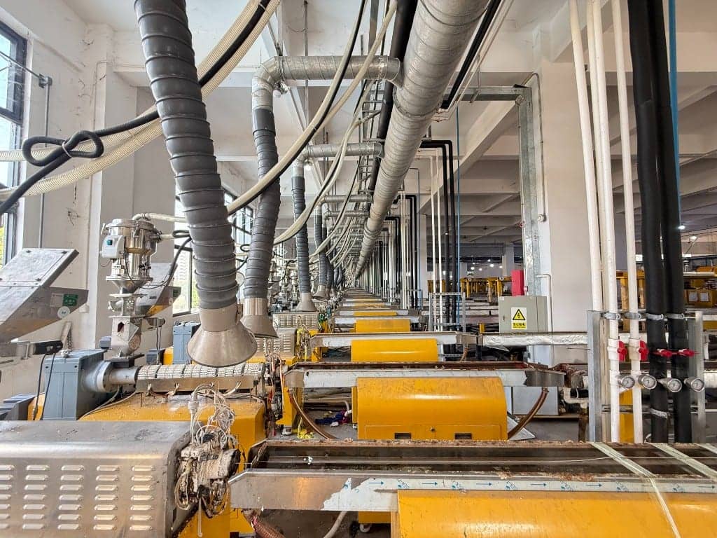 PLA PETG filament production line OEM factory Foshan — yellow extruder barrels and cooling path in a source plant